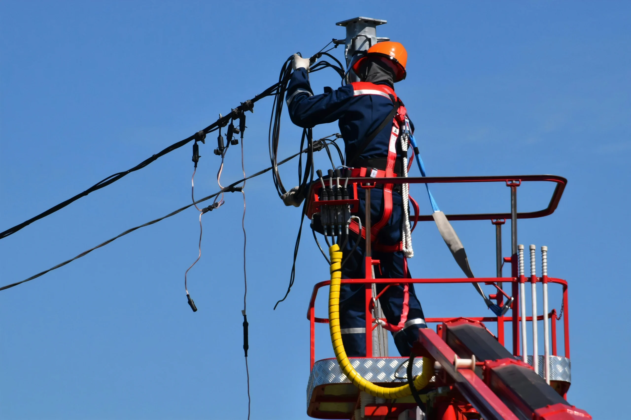 Technician performs maintenance on an overhead power line, highlighting the fragility of the energy system