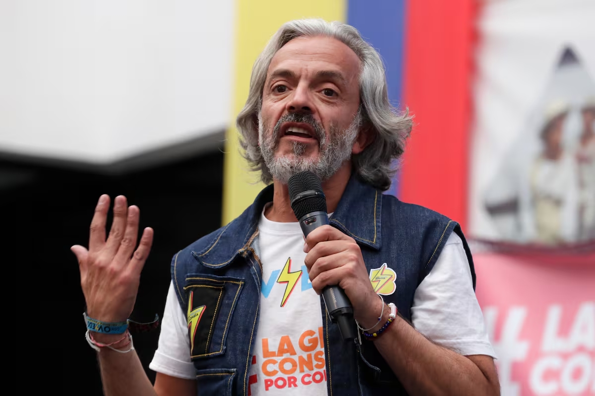 Juan Daniel Oviedo y el rayo de su campaña Juan Daniel Oviedo hablando en un evento de campaña en Colombia, vistiendo una camiseta con un rayo que representa energía y renovación política.