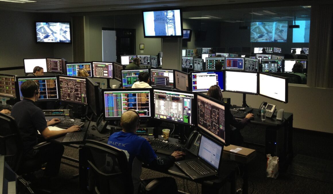 Control room with multiple screens monitoring infrastructure and real-time data