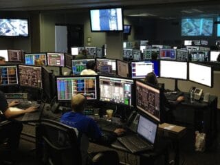 Control room with multiple screens monitoring infrastructure and real-time data