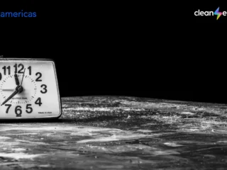 Vintage black-and-white alarm clock surrounded by darkness, with the BNamericas and Clean Energy logos.