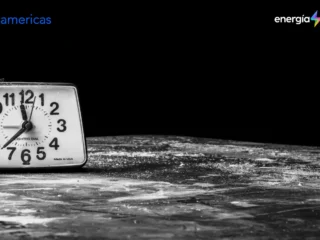 Reloj despertador antiguo en blanco y negro, rodeado de oscuridad, con los logos de BNamericas y Energía Limpia.