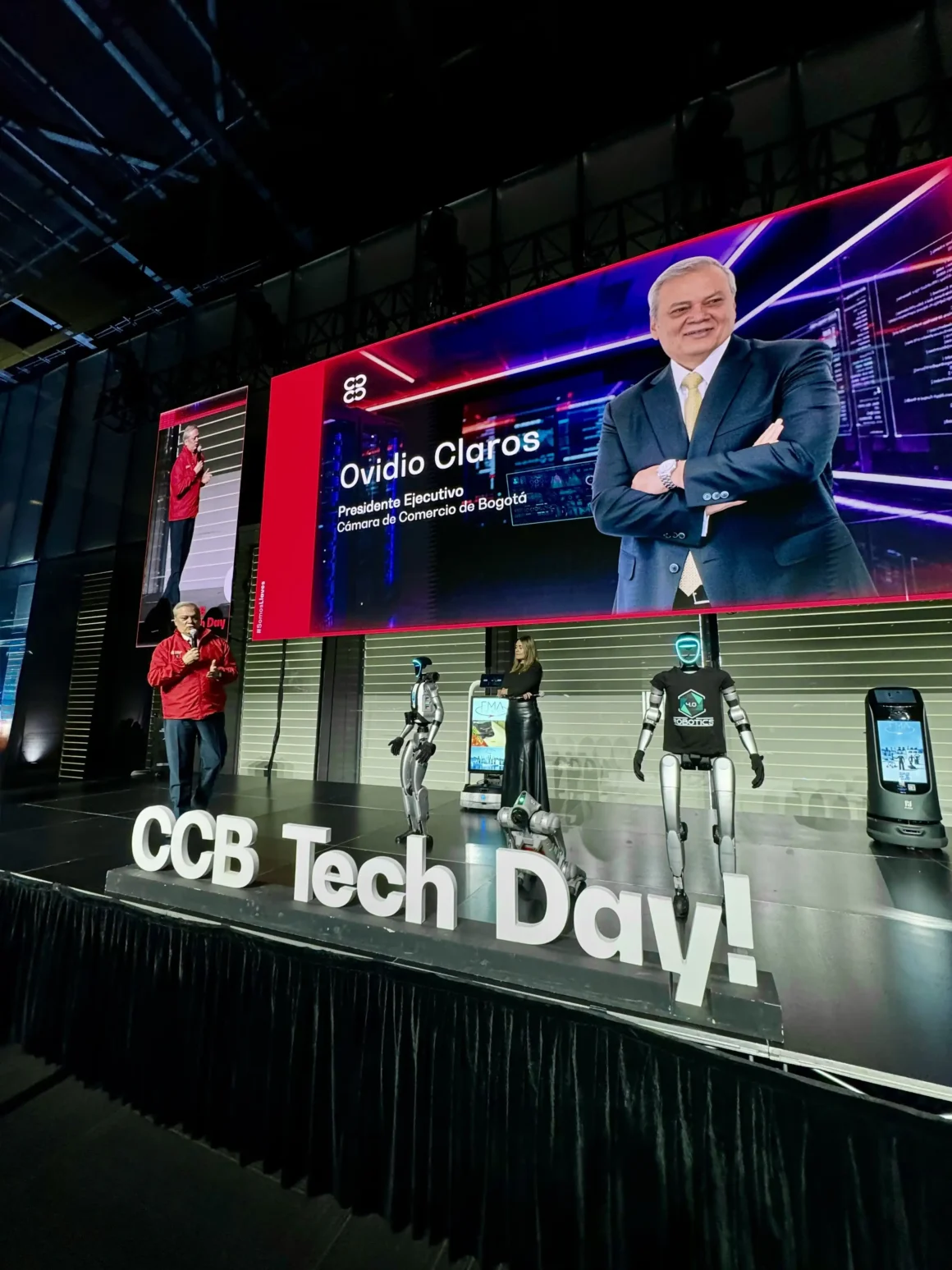 Escenario del CCB Tech Day 2026 en Ágora Bogotá, con Ovidio Claros y varios robots humanoides frente al público.