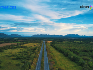Aerial view of a highway crossing Colombia’s green landscape toward the mountains, with the BNamericas and Clean Energy logos.
